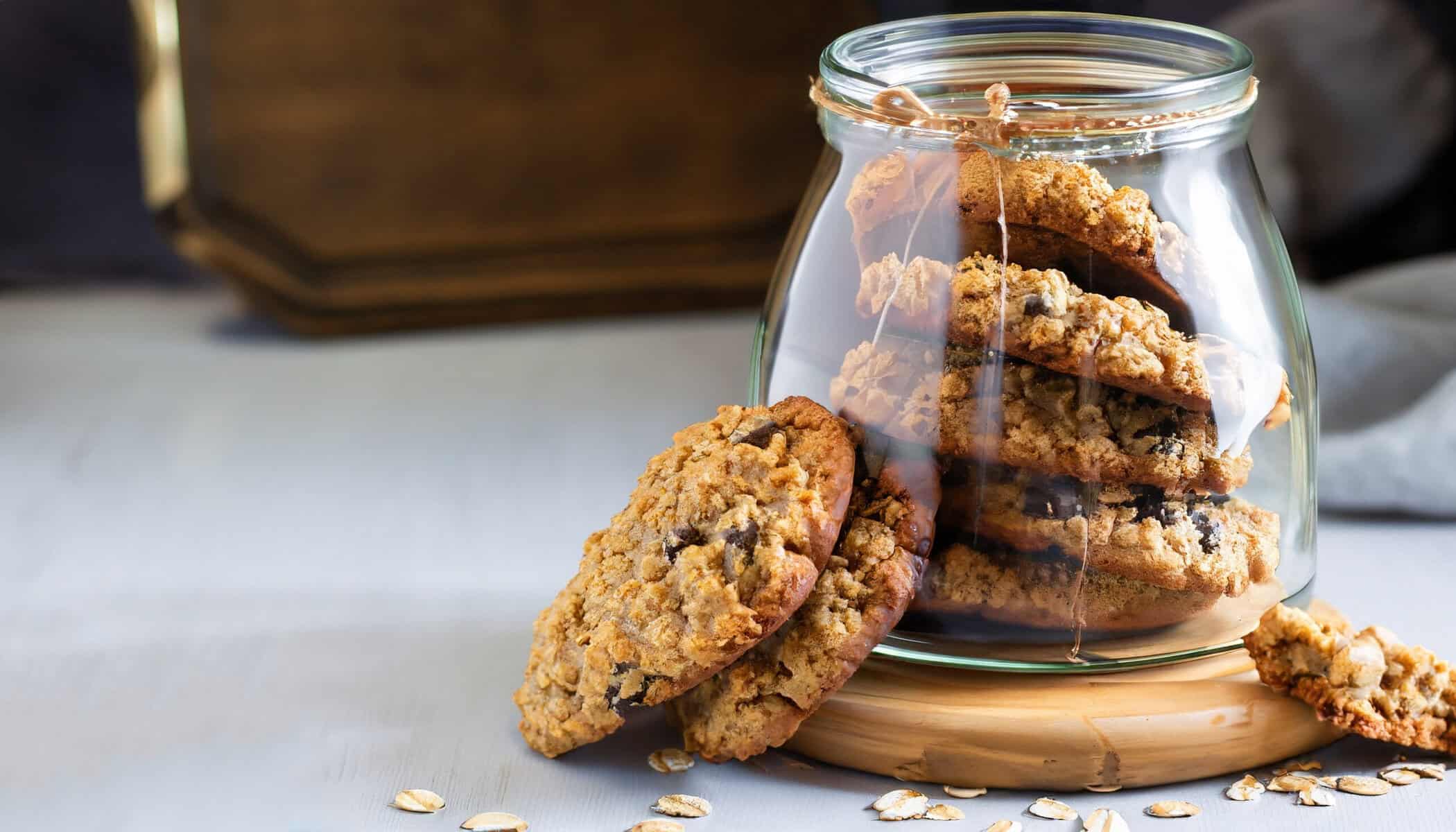 Flourless gluten free peanut butter, oatmeal and chocolate chips cookies in glass jar and on table, horizontal cookie jar